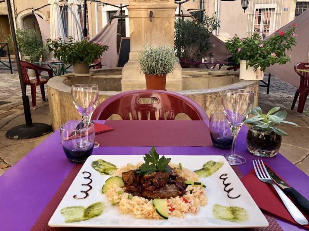 Une assiette de viande en sauce, avec une garniture de riz, sur une table violette
