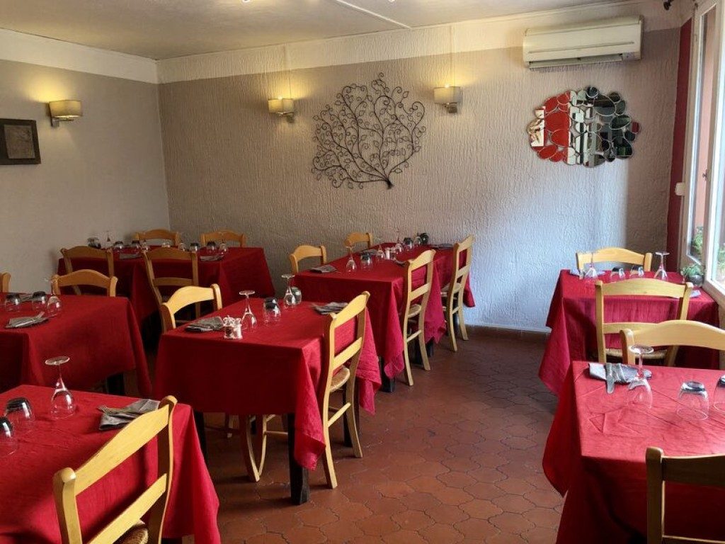 La salle du restaurant : nappes rouges, chaises en bois et murs clairs